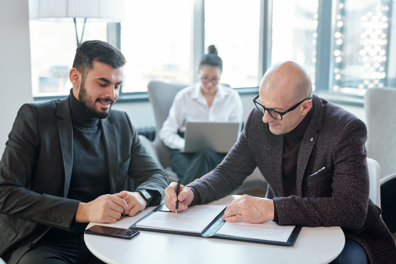 Two successful business partners signing financial documents in hotel lounge